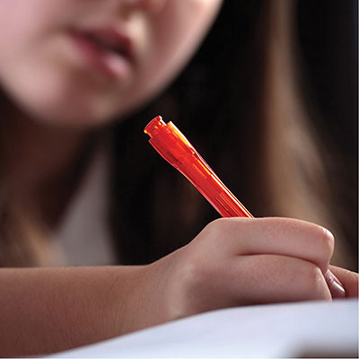 A photo of a child writing with a pen